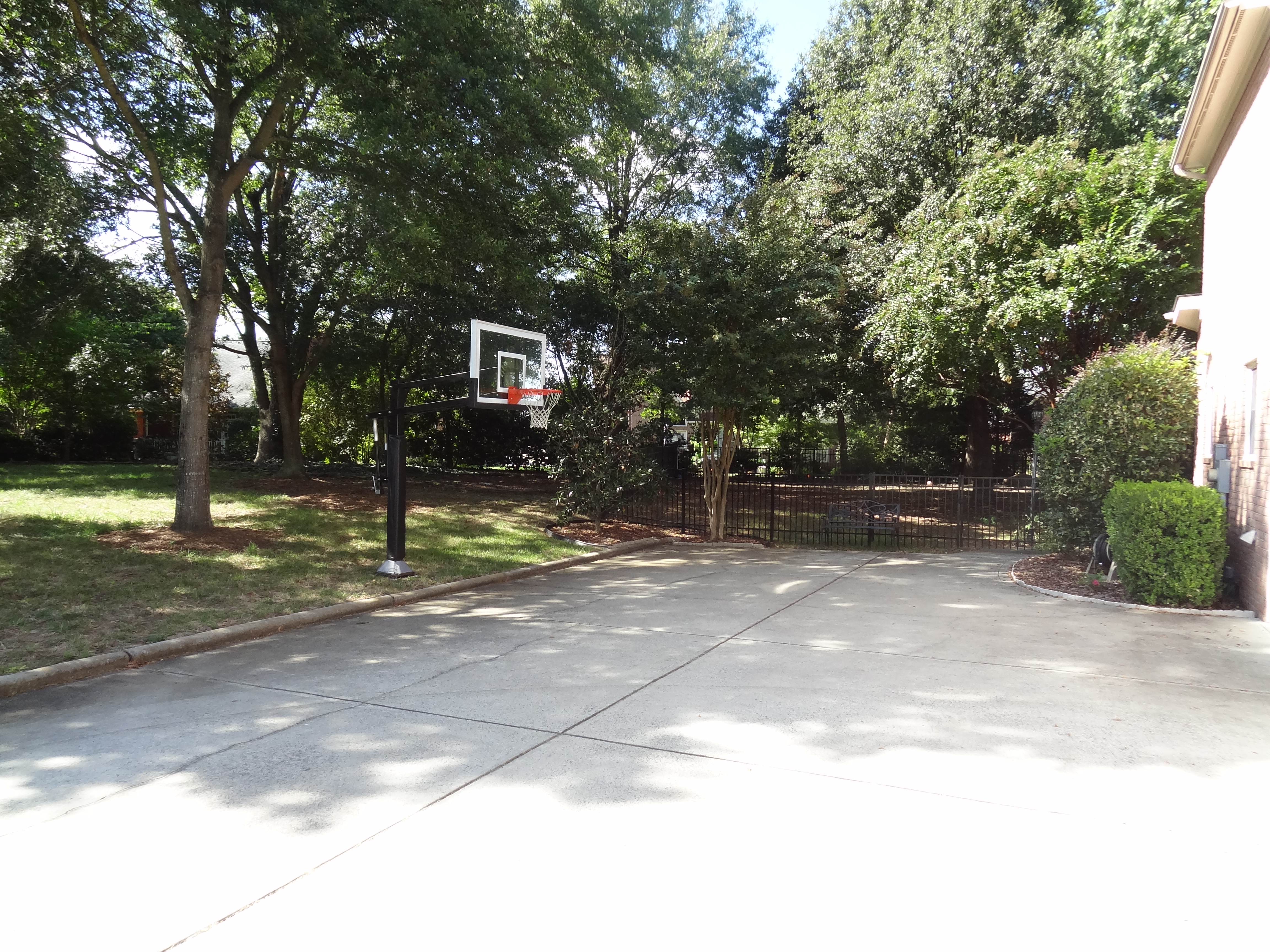 This long view wide shot shows a Pro Dunk Gold Basketball installed neatly next to the driveway of this North Carolina home.