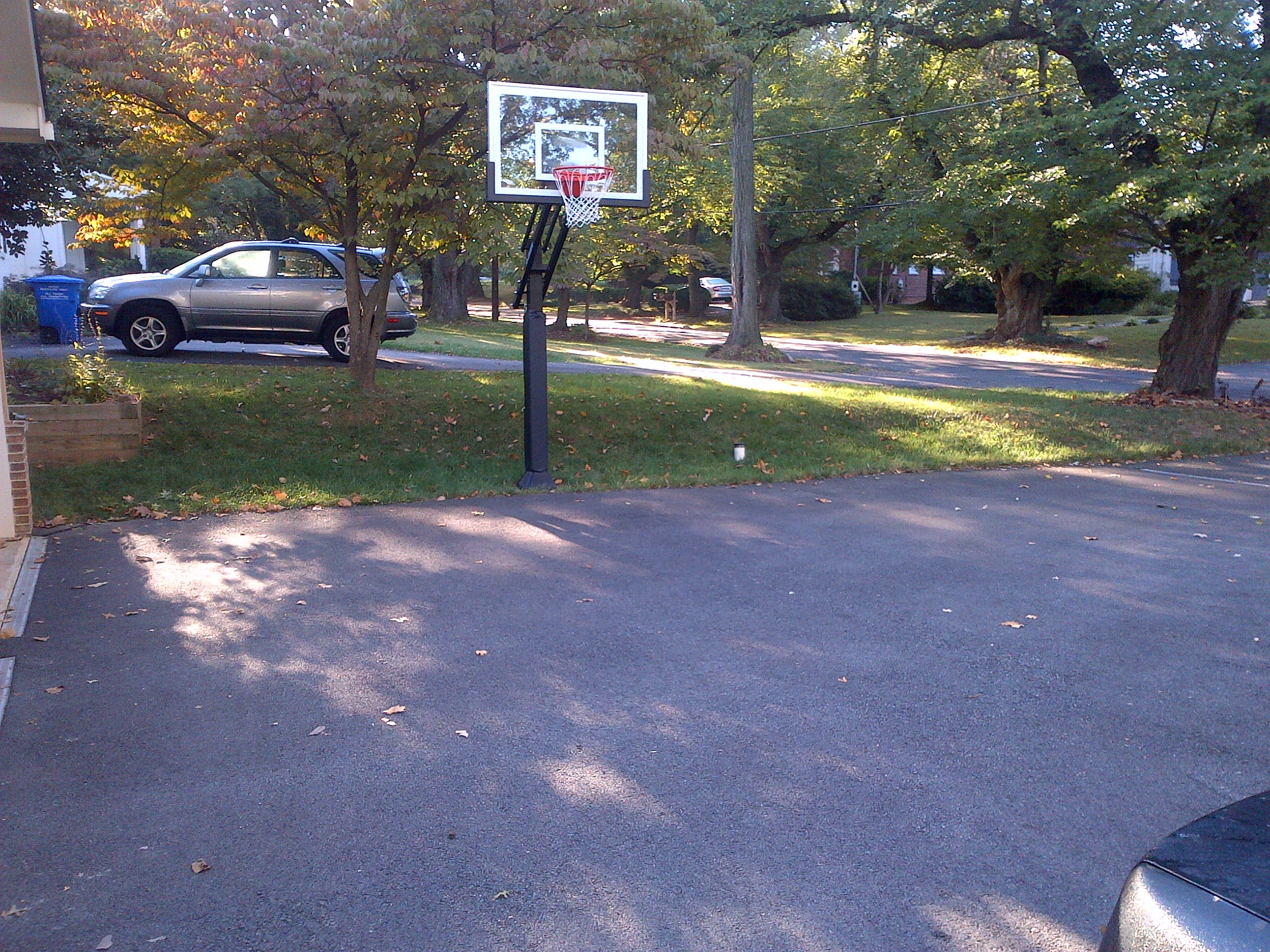 There is a Pro Dunk Silver Basketball that is assembled nicely on the side of the asphalt concrete driveway in front of his residence.