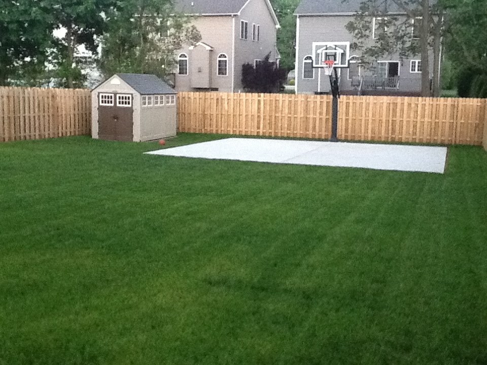 Beautiful green grass surrounds a new basketball court.