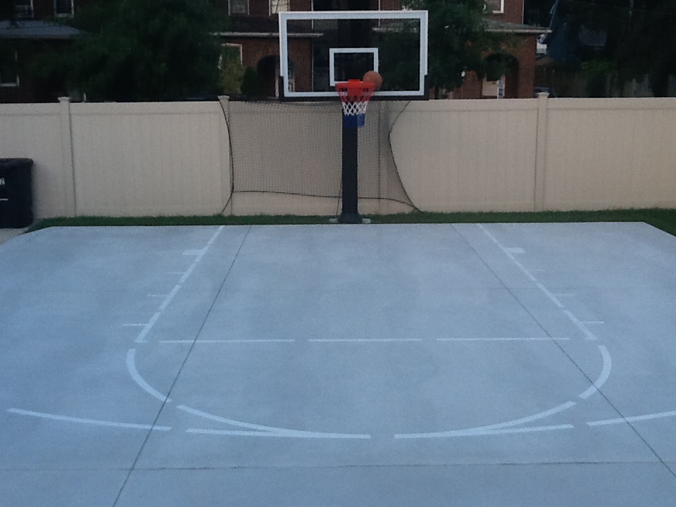 The Pro Dunk Platinum basketball system is backed up to a cream colored fence.