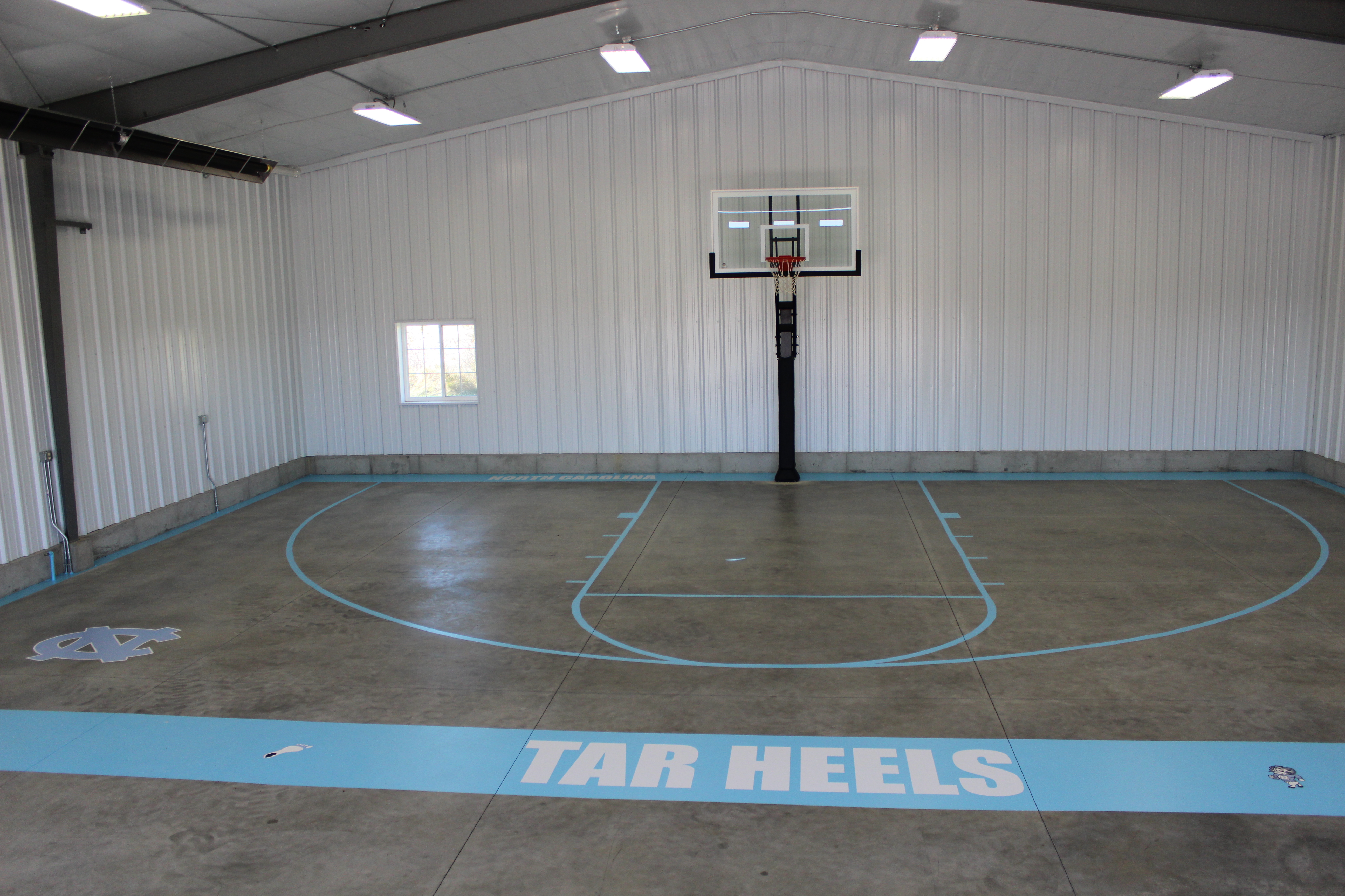 This Pro Dunk Platinum basketball system sits in an indoor gym, on concrete floor.
