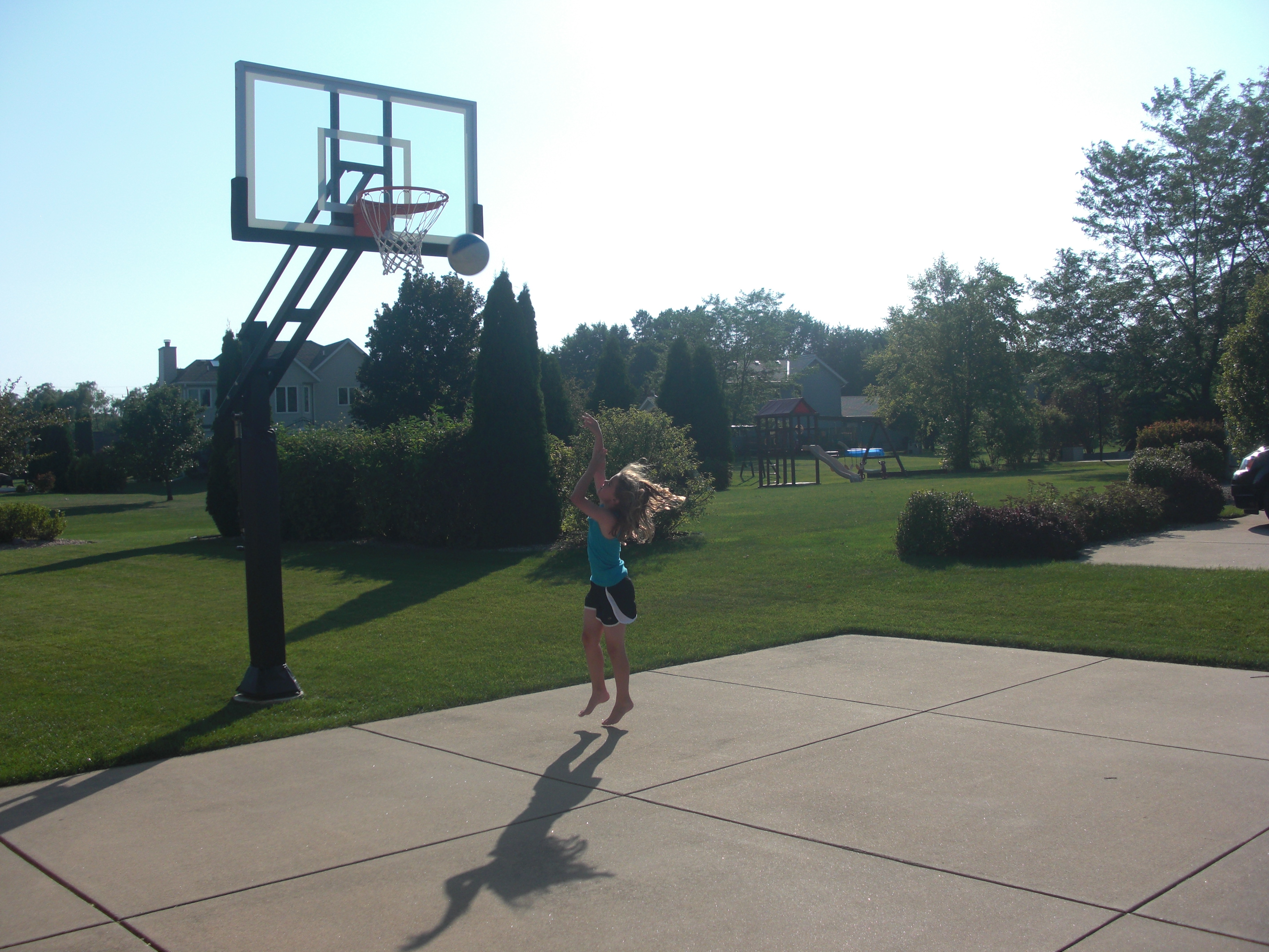 Third in a series of action photos of what looks to be a successful layup on a beautiful backyard basketball court.