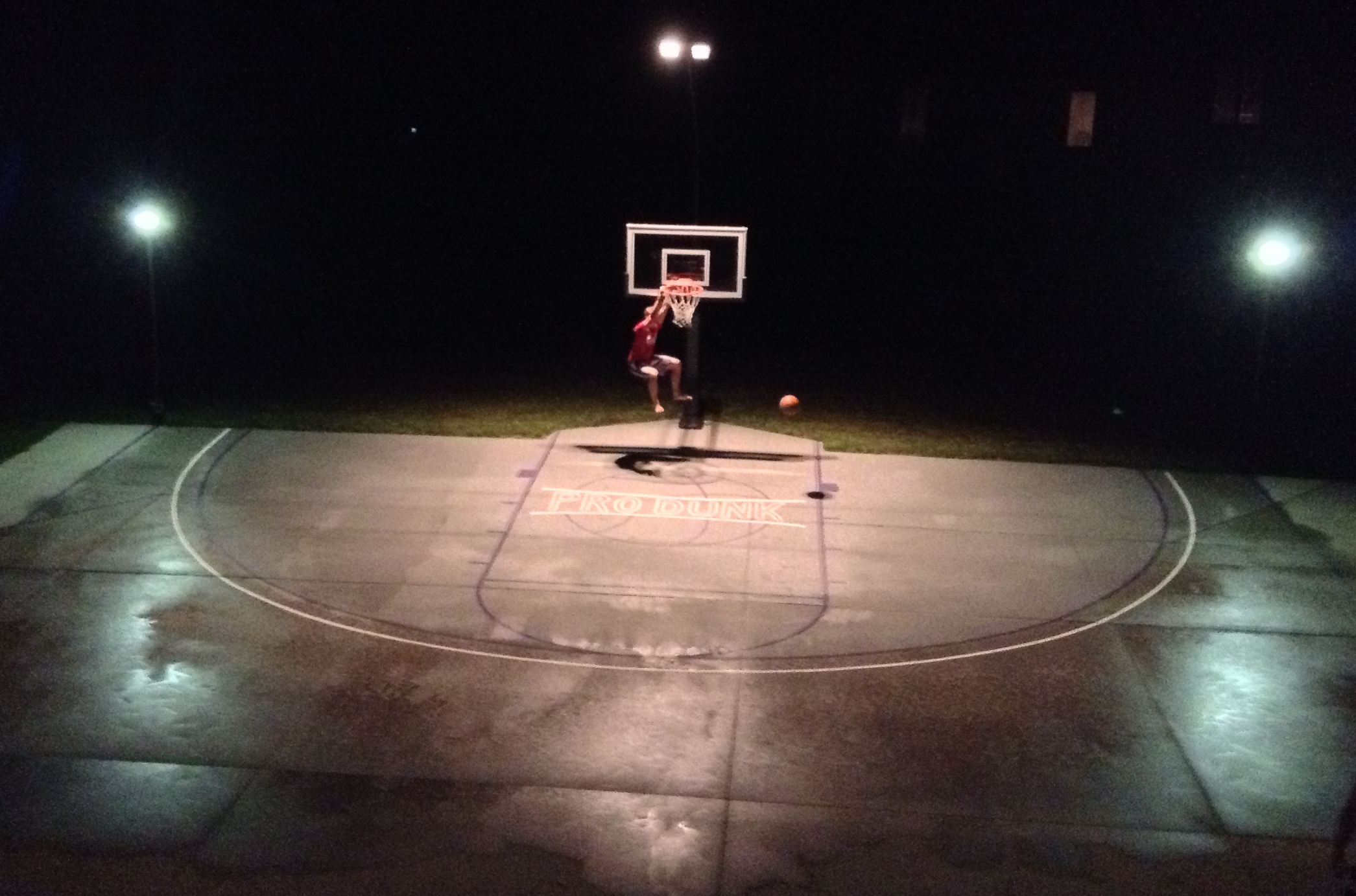 A teenage boy slam dunks Pro Dunk Gold Basketball System.